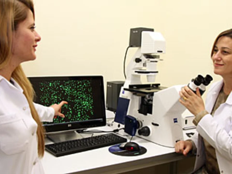 Dr. Ebru Erbay in front of a microscope, discussing the results of an imaging procedure